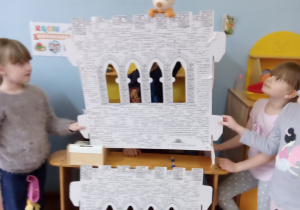 Czworo dzieci składa teatrzyk kukiełkowy - zamek.